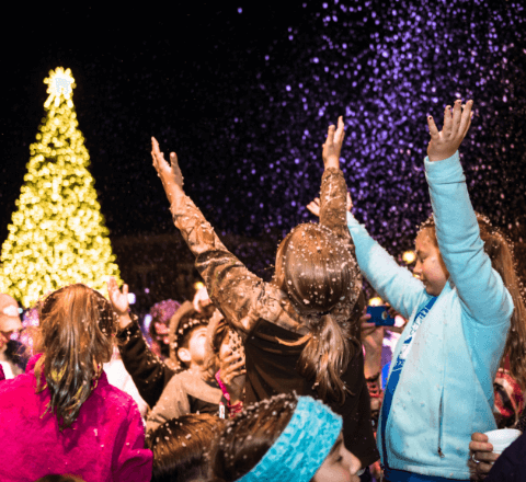 Children reaching to the sky to enjoy the fake snow at Tree lighting