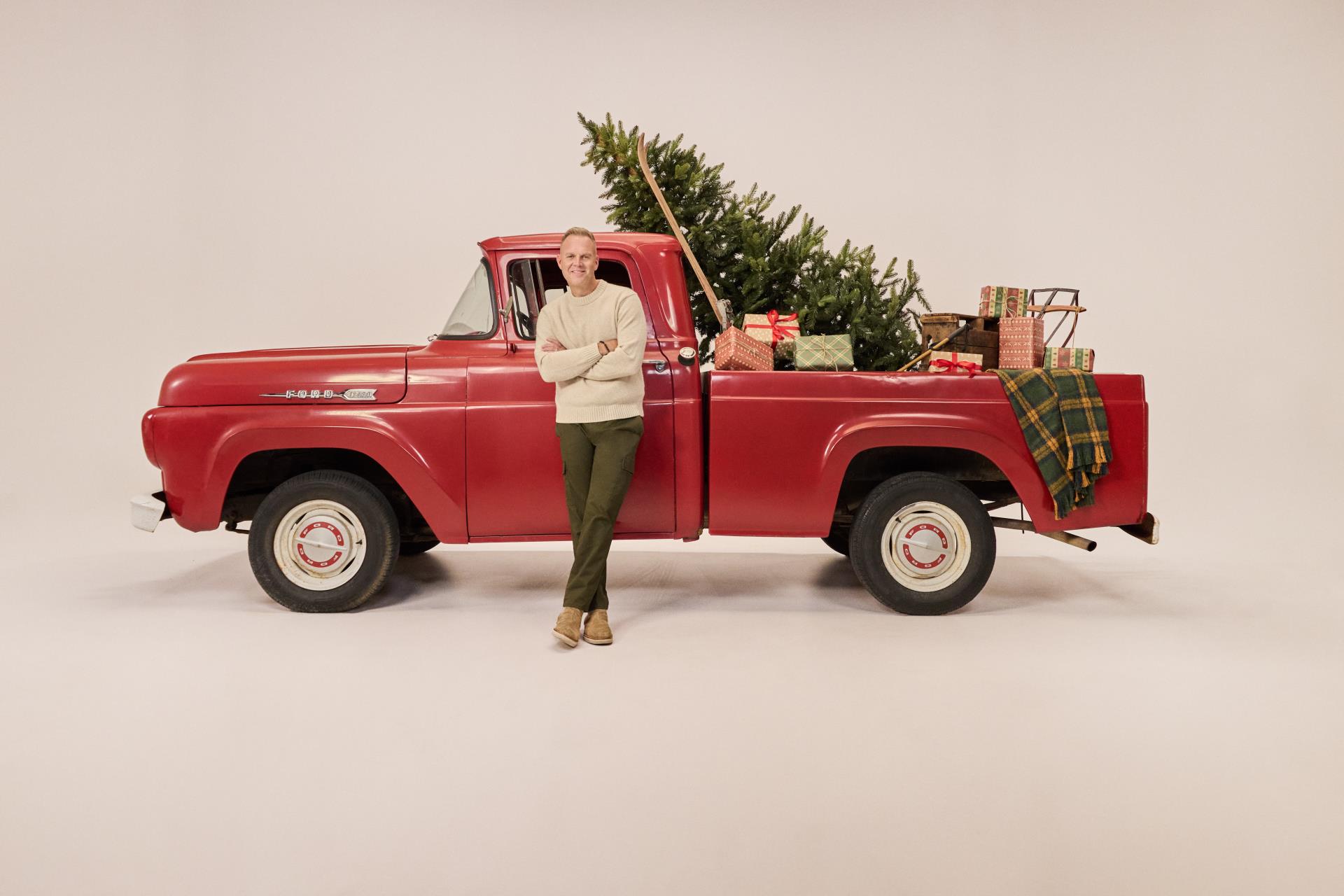 Singer Mathew West stands in front of red truck with Christmas Tree in Back